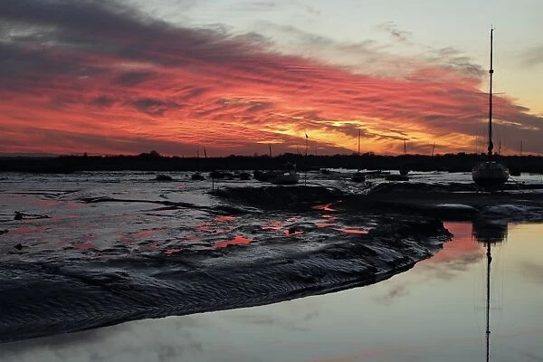 Boats on mud in coastal creek during low tide at sunset, Leigh-on-Sea, Thames Estuary, Essex, England, December