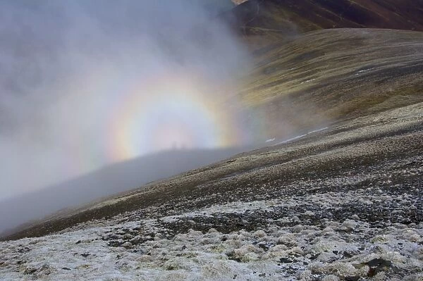 Brocken spectre seen from hilltop, appears when sun shines from behind person who is looking down from ridge or peak