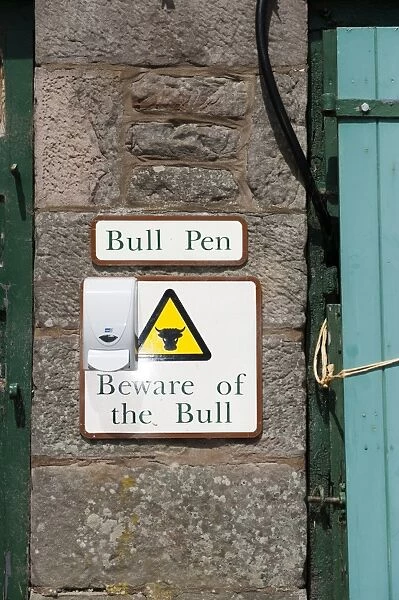 Bull Pen and Beware of the Bull warning signs on wall of farm building, England, May