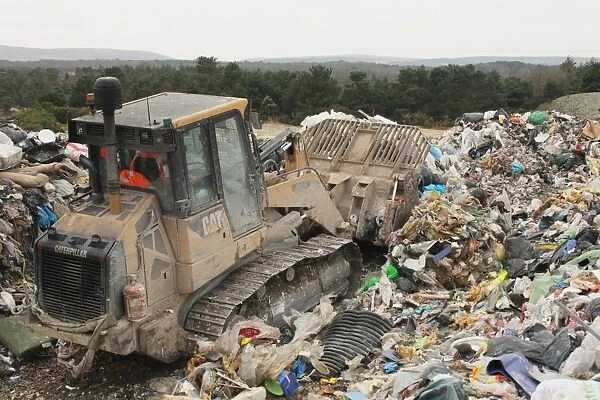 Bulldozer moving rubbish on landfill tip, Dorset, England, February