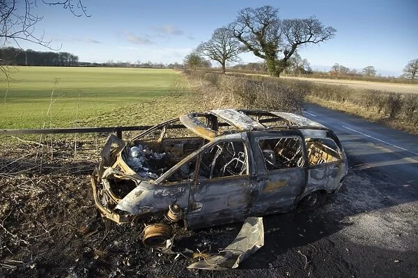 Burnt-out vehicle in farm gateway, Skipwith, North Yorkshire, England, january