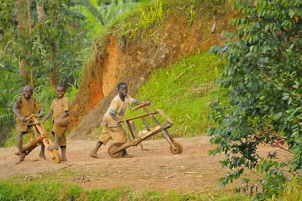 Children playing with wood-made bicycles on track at edge of Nyungwe Forest N. P. Rwanda, march