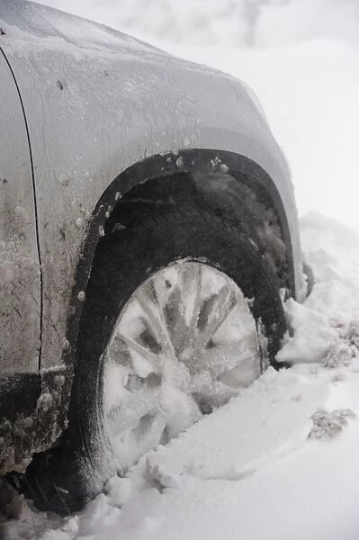 Close-up of car wheel stuck in snowdrift after snowstorm, Cumbria, England, March