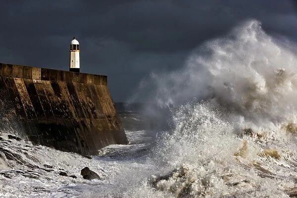 Coastal resort town seafront and lighthouse bombarded by waves during storm, Porthcawl Pier, Porthcawl