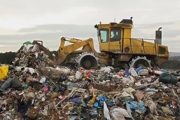 Compactor moving rubbish on landfill tip, Dorset, England, February