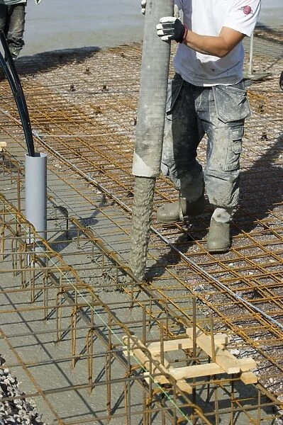 Construction work on farm building for loose housing, concrete being poured onto reinforcing bars for flooring, Sweden