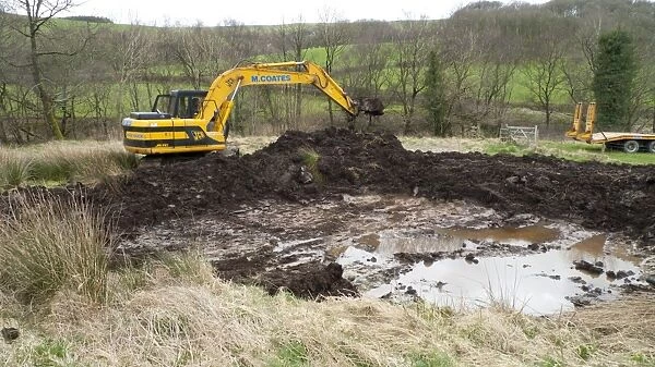 Contractor with 360degree excavator, digging wildlife pond on farm, Powys, Wales, April
