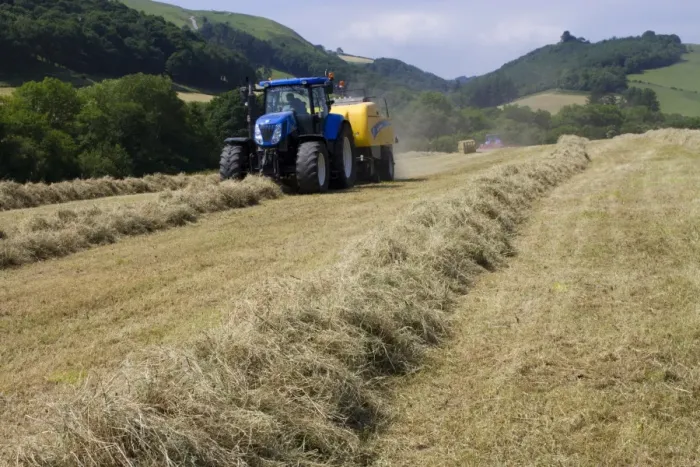 Framed Print : Contractor with New Holland T7040 tractor and New Holland big-square baler, baling hay on organic farm, Powys, Wales