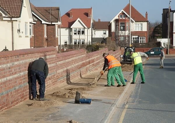 Council workers clearing away sand blown from beach and dunes onto road and pavement in seaside resort town, Lytham St. Anne's, Lancashire, England, january
