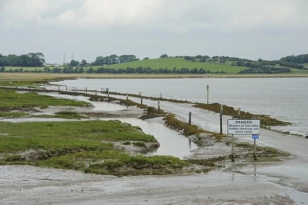 Danger, Beware of fast tides, hidden channels and quick sands warning sign beside road from coastal village