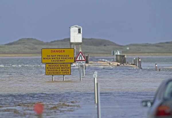 Danger, do not proceed when water reaches causeway sign on causeway underwater at high tide, Lindisfarne