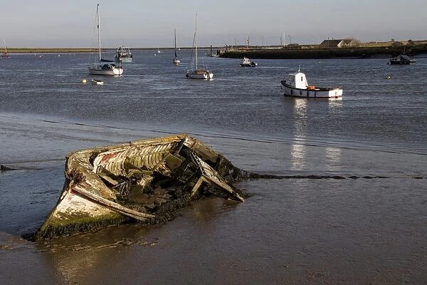 Decaying old boat on mud in The River Alde by Orford, looking east over Orford Ness, Suffolk