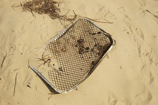Disposable barbeque, litter on coastal sand dune, Studland, Dorset, England, may