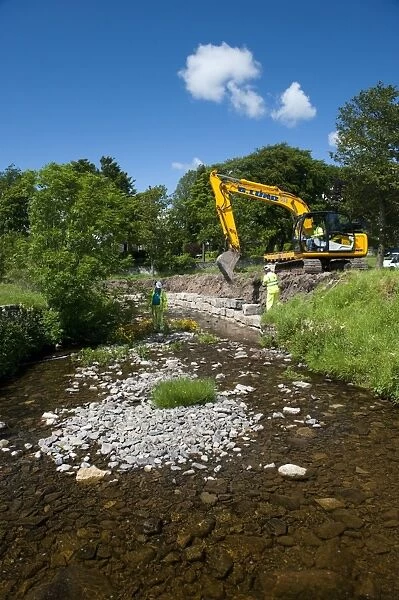 Excavator improving stream bank to help prevent flooding, Cumbria, England, june