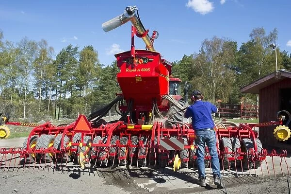 Farmer washing Vaderstad Rapid A 600S seed drill with pressure washer, Upplands Vasby, Sweden, may