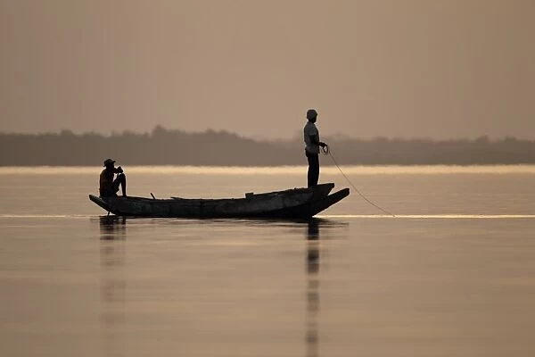 Fishermen in boat on river at sunset, River Gambia, Tendaba, Gambia, february