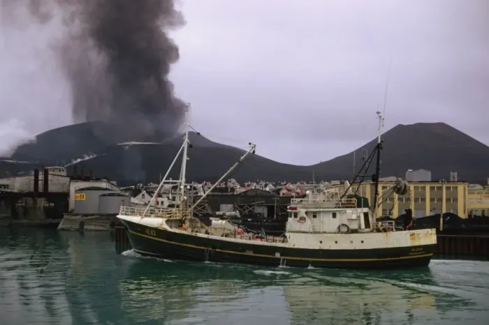 Framed Print : Fishing boat leaving harbour, with ash raising from erupting volcano in background, Eldfell Volcano, Heimaey Framed Print : Fishing boat leaving harbour, with ash raising from erupting volcano in background, Eldfell Volcano, Heimaey
