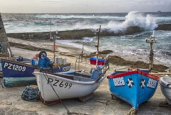 Fishing boats in coastal village, with waves breaking over breakwater, Sennen Cove, Sennen, Cornwall, England, May
