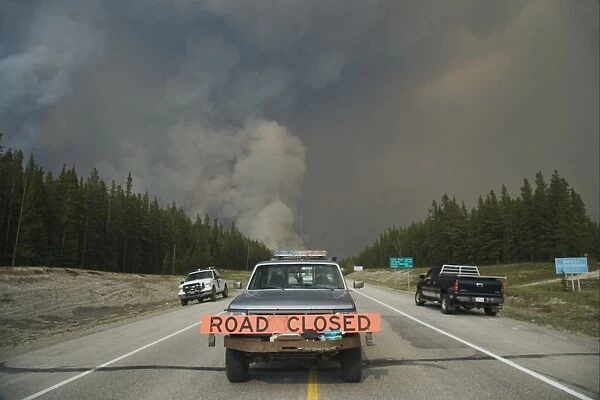 Forest fire, controlled burn beside road, Road Closed sign on pickup truck, Saskatchewan Valley, Banff N. P. Rocky Mountains, Alberta, Canada, june 2009