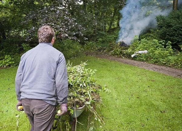 Gardener burning garden rubbish on bonfire, Chipping, Lancashire, England, august