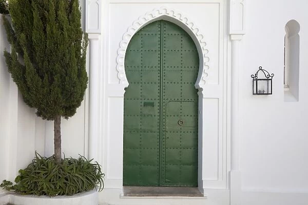 Green door and lantern in street of coastal city, Tangier, Morocco, april