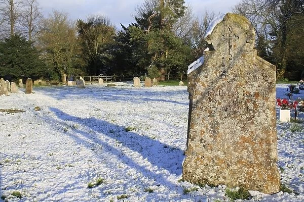 Headstones in snow covered church graveyard, St. Marys Church, Bacton, Suffolk, England, november
