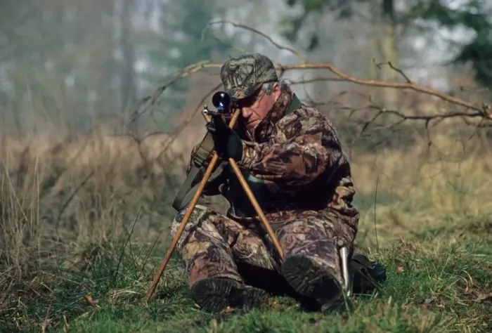 Framed Print : Hunting, deer stalker sitting on low seat and using tripod to support rifle, England Framed Print : Hunting, deer stalker sitting on low seat and using tripod to support rifle, England