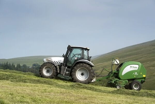 Hurlimann tractor with McHale round baler, baling on steep upland meadow, Cumbria, England, July