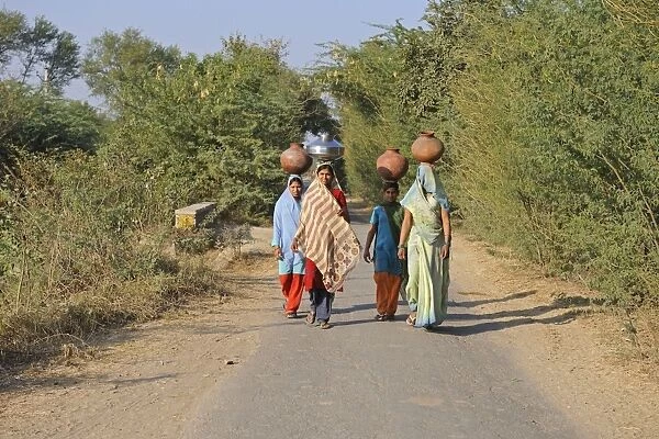 Indian girls carrying water containers on heads, near Bharatpur, Rajasthan, India, December