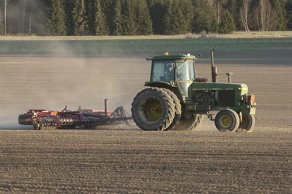 John Deere 4240 tractor with harrows, harrowing field seedbed, Sweden, may