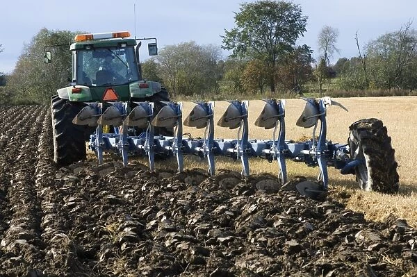 John Deere 8400 tractor pulling eight furrow reversible plough, ploughing stubble field, Sweden, autumn