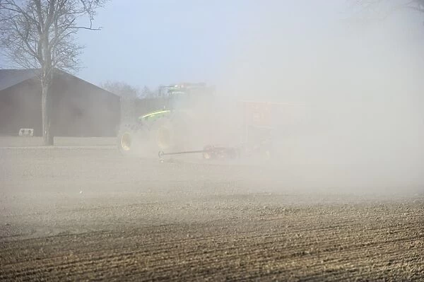 John Deere 8530 tractor with Vaderstad seed drill, with wind blown dust in field, Tierp, Uppland, Sweden, may