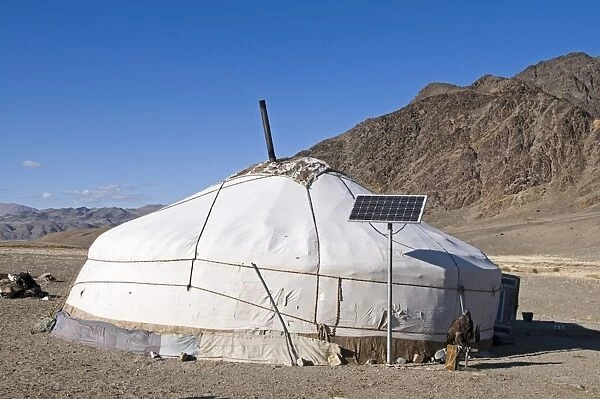 Kazakh nomad ger tent with solar panel and hooded Golden Eagle (Aquila chrysaetos) outside, Altai Mountains