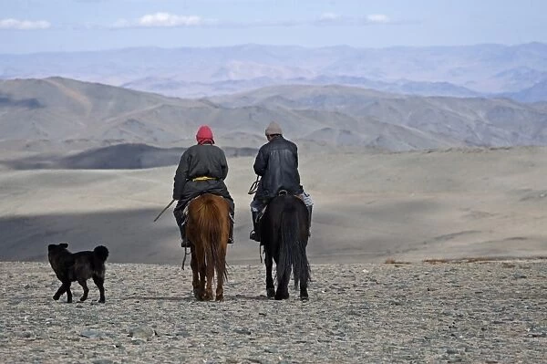 Two Kazakh nomads on horseback with dog, Altai Mountains, Bayan-Ulgii, Western Mongolia, october