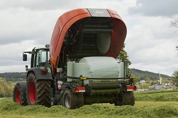 Kuhn all in one baler and wrapper, wrapping round silage bale in plastic, Cumbria, England, May