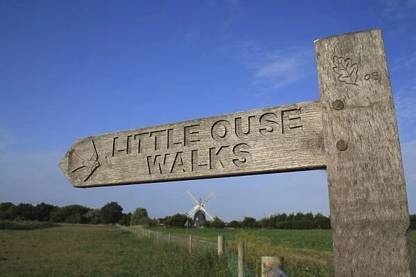 Little Ouse Walks wooden direction sign, beside fen meadow with windmill in background, Little Ouse Headwaters Project