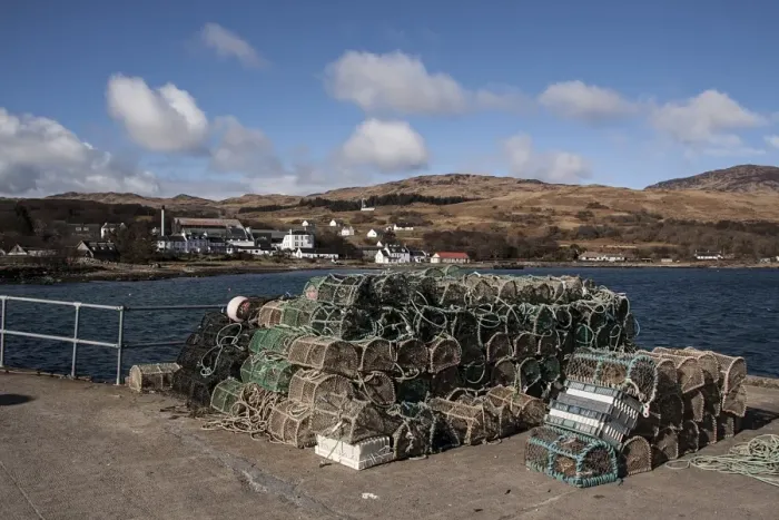 Framed Print : Lobster pots on Jura Pier with Jura Hotel and whiskey distillery behind Framed Print : Lobster pots on Jura Pier with Jura Hotel and whiskey distillery behind