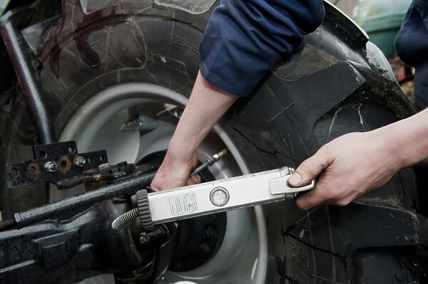 Mechanic checking tyre pressure in tractor tyres, England, october