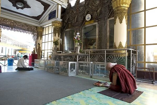 Monk with tattoo, praying in temple, Yangon, Myanmar, March