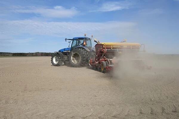 New Holland TM150 tractor with Vaderstad seed drill, with wind blown dust in field, Sweden, may