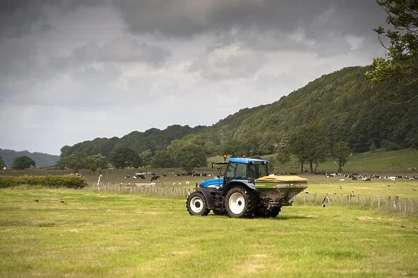 New Holland tractor with Amazone spreader, spreading fertiliser on meadow after taking crop of silage