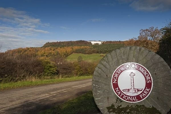 North York Moors National Park sign on millstone, with Kilburn White Horse hill figure on hillside in background