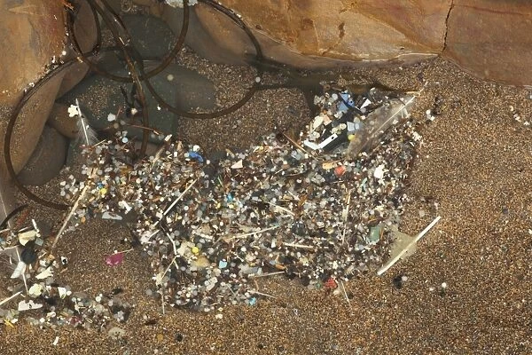 Nurdles, plastic pellets and other broken down plastic debris in shallow pool on beach, Bude, Cornwall, England