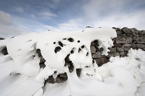 Patterns in snowdrift at back of drystone wall after snowstorm, Cumbria, England, March