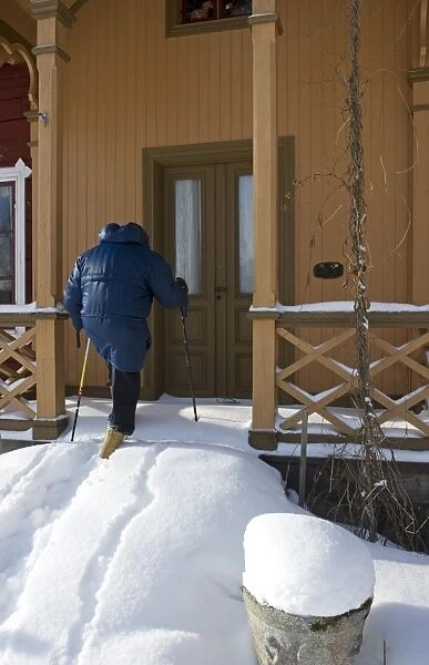 Person walking up snow covered steps to house door, Sweden, february
