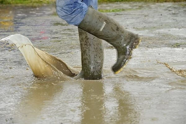 Person walking with wellington boots through puddle at agricultural show, Yorkshire, England, July