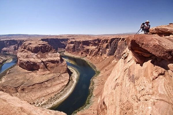 Photogarpher at the Horseshoe bend overlook, the Colorado River in Glen Canyon is making a 270 curve in an entrenched
