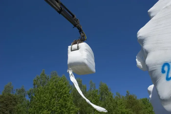 Framed Print : Plastic wrapped silage bales, loaded onto truck with mechanical grabber, Sweden, may