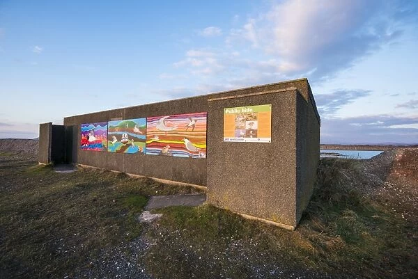 Public hide overlooking flooded former iron ore mining area, surrounded by sea wall on outskirts of Millom