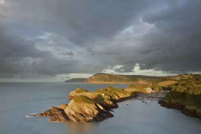 Framed Print : Rainclouds gathering over rocky coastal peninsula and bay in evening, with Great Hangmans and Combemartin in distance Framed Print : Rainclouds gathering over rocky coastal peninsula and bay in evening, with Great Hangmans and Combemartin in distance
